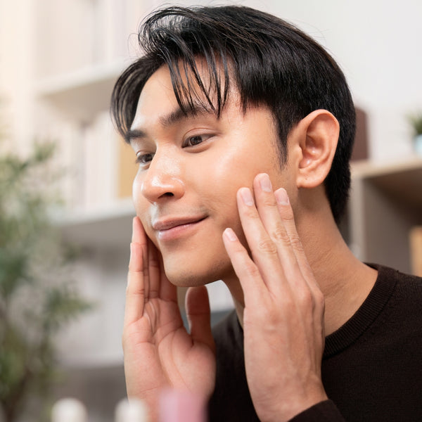 Man applying cream to his face with a blurred indoor background